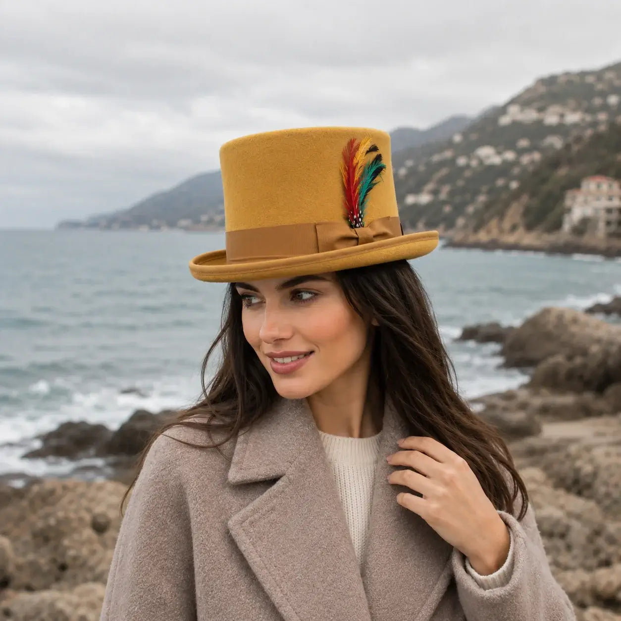 Woman wearing a mustard yellow top hat with a feather on a rocky coastline.