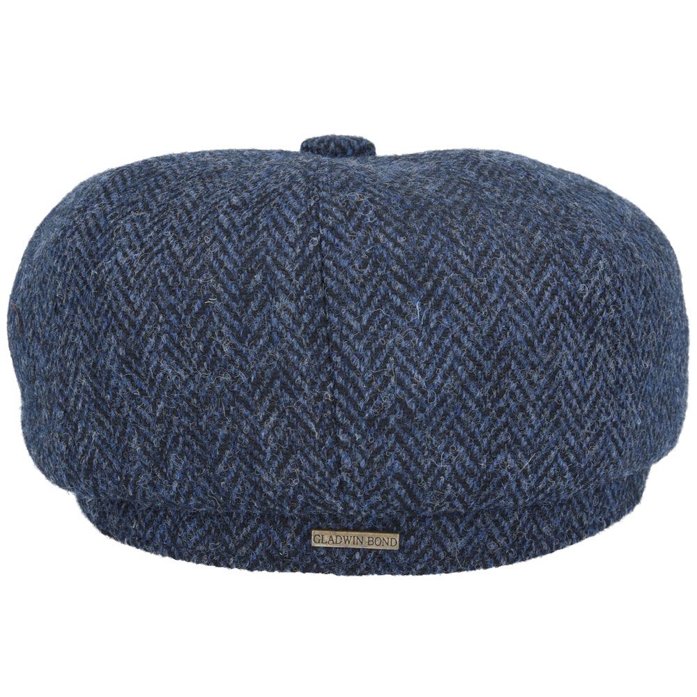 Navy Harris Tweed Herringbone Newsboy Cap, crafted from 100% pure new wool, handwoven in Scotland’s Outer Hebrides. Features include a sewn-down brim, cotton lining, and a removable Gladwin Bond side pin. Available in sizes S-XL. Inspired by the iconic Peaky Blinders style.